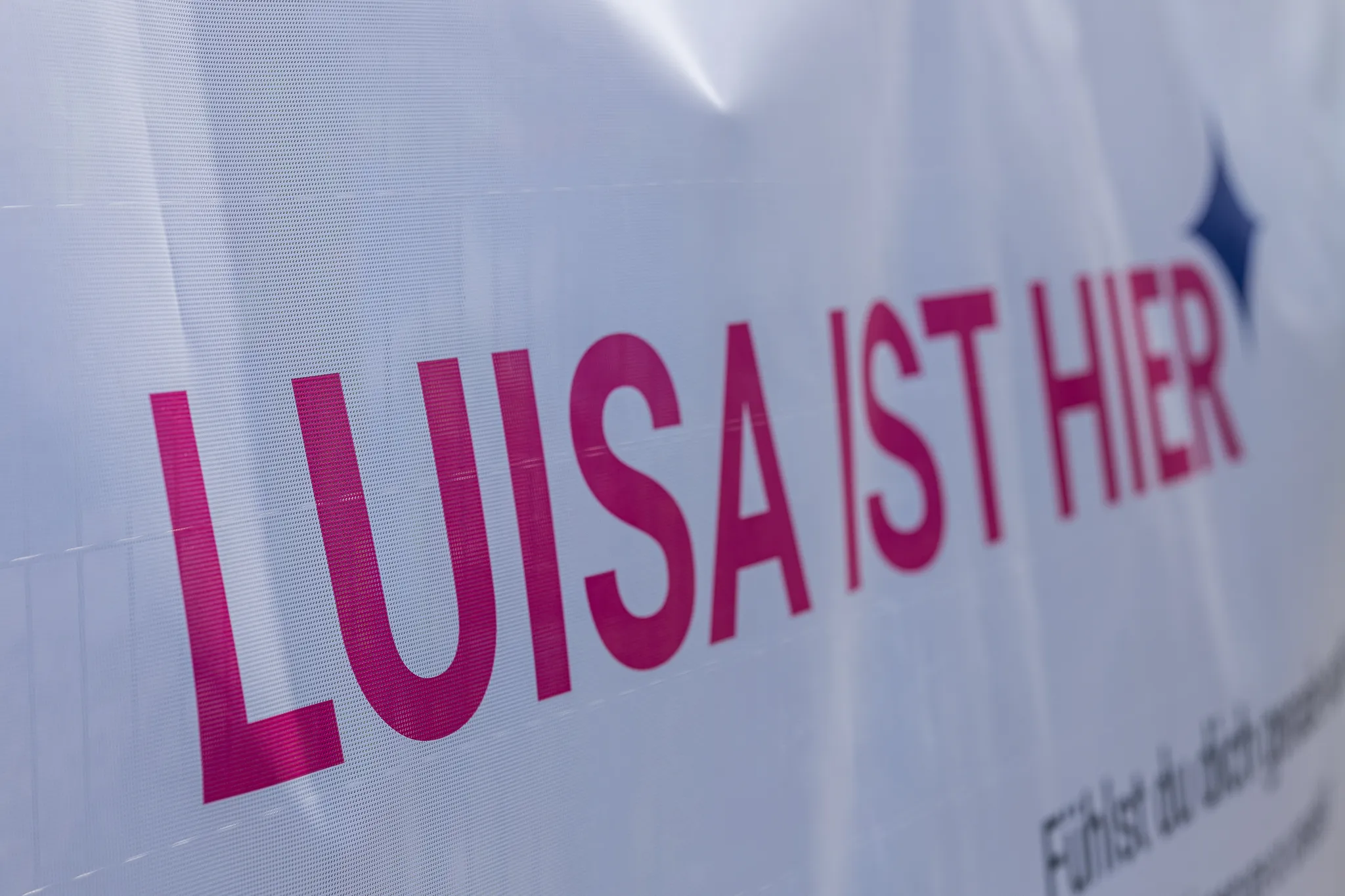 Nahaufnahme eines Banners mit der Aufschrift 'Luisa ist hier'.