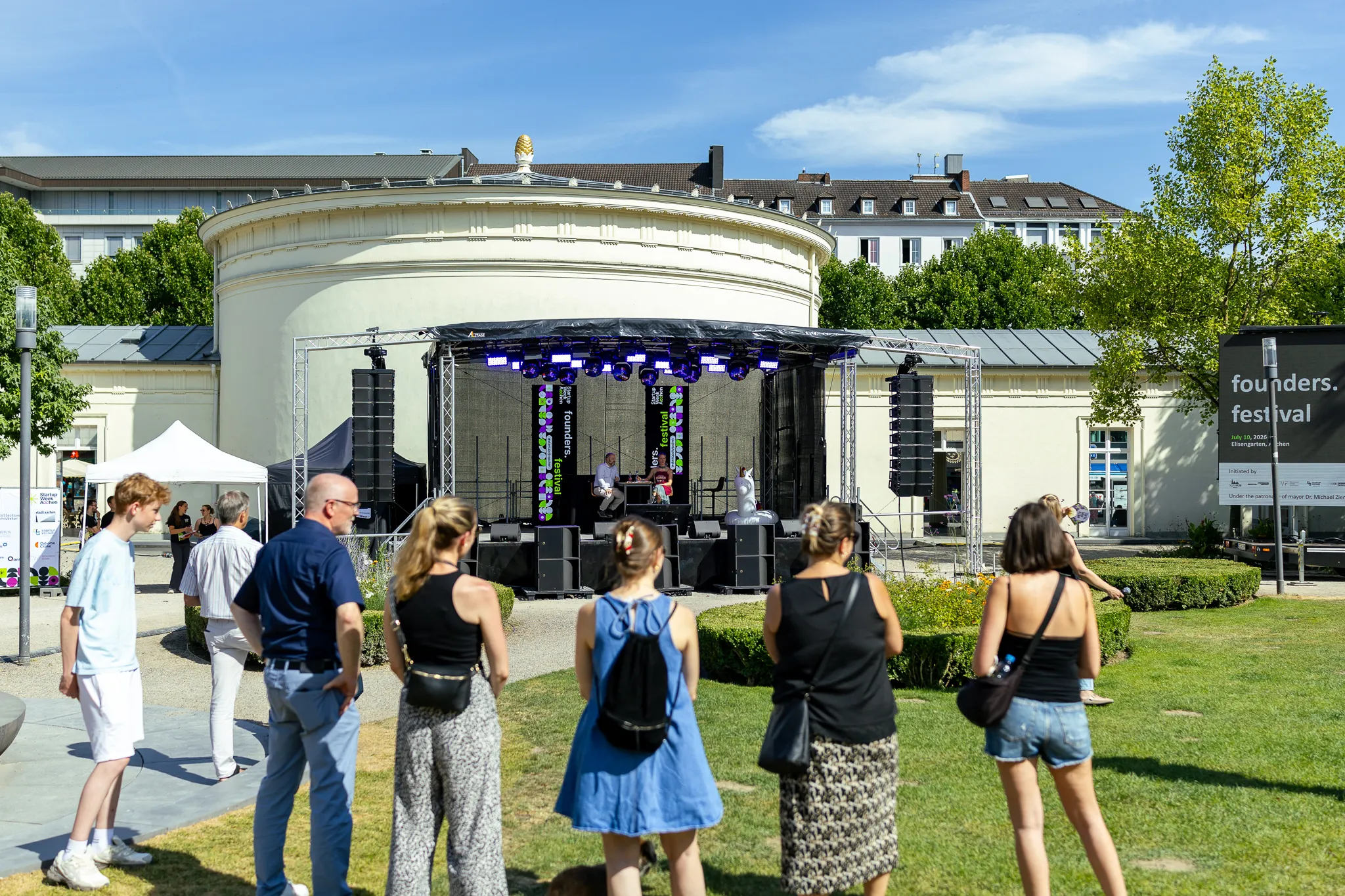 Bürgerinnen und Bürger stehen im Halbkreis und stellen Fragen bei Grill den OB! im Elisengarten.
